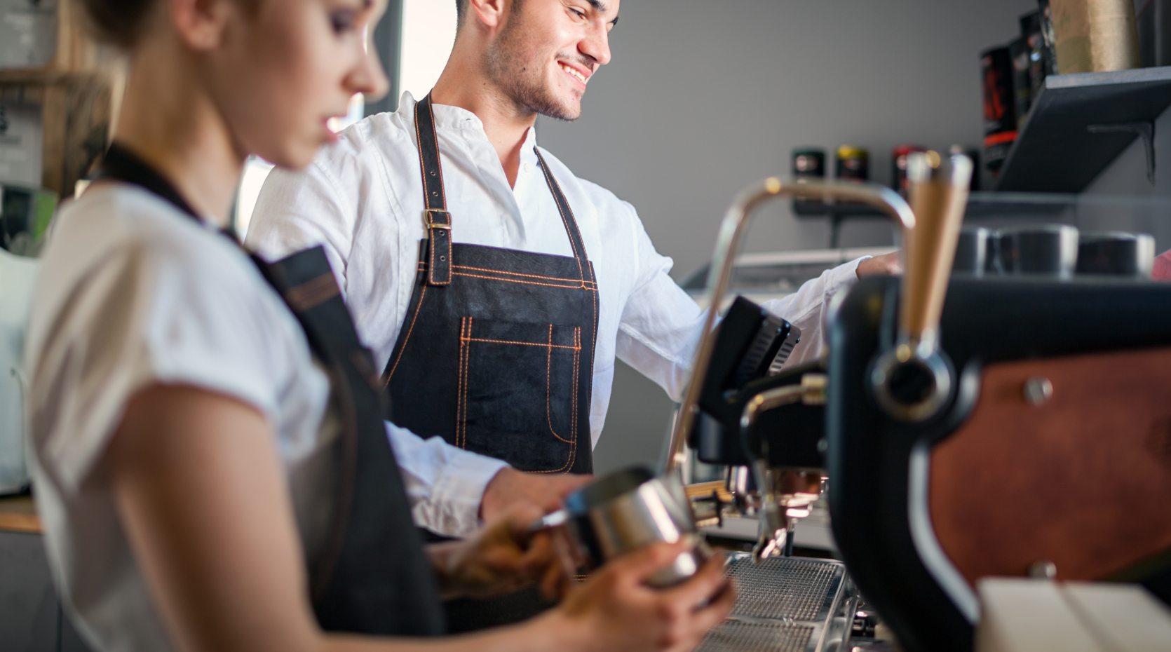 Två personer står vid en kaffemaskin